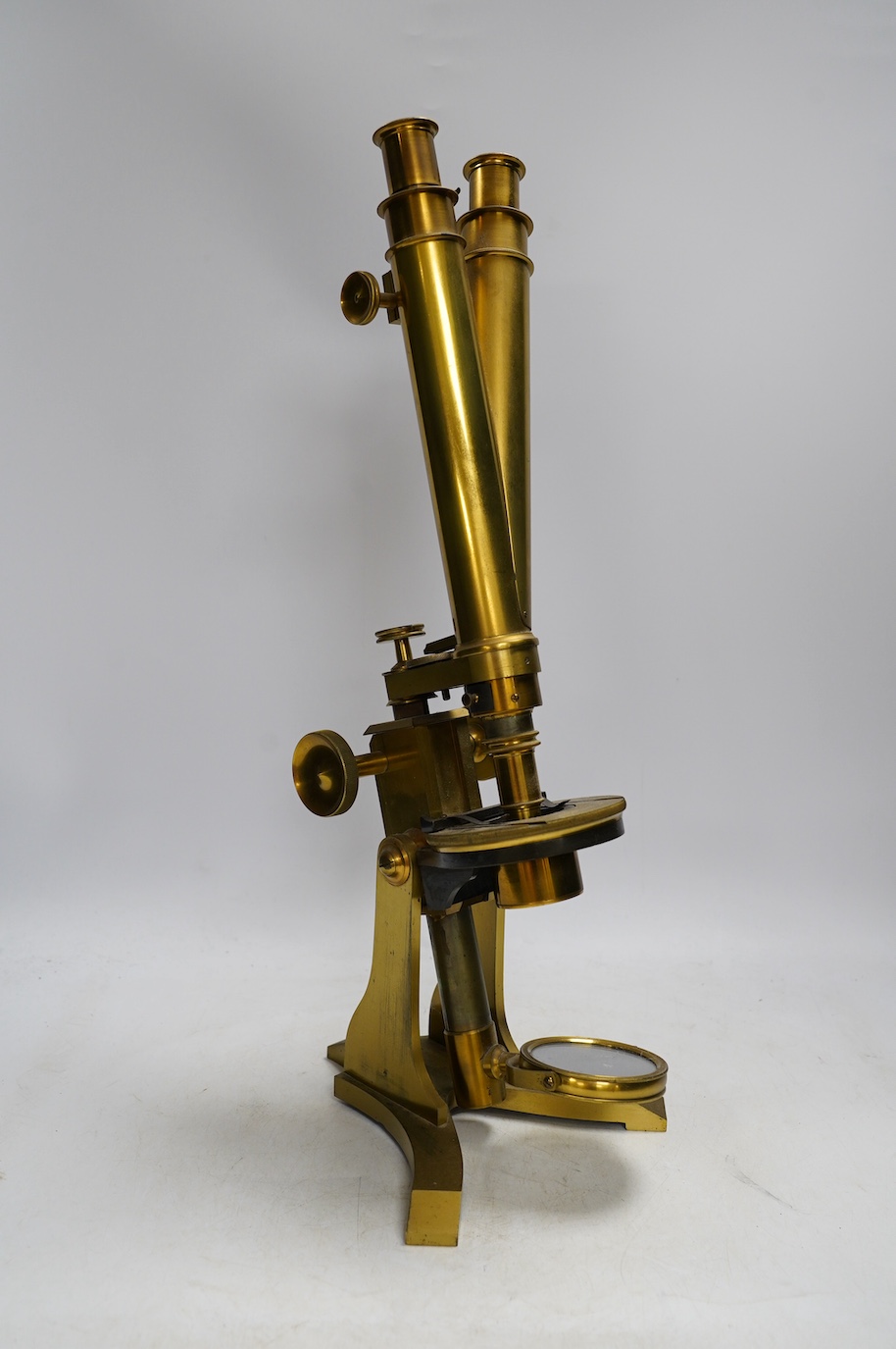 A 19th century brass compound binocular microscope, engraved to the base Baker, 244 High Holborn, London, with four brass cased objective lenses, 47cm high. Condition - fair to good